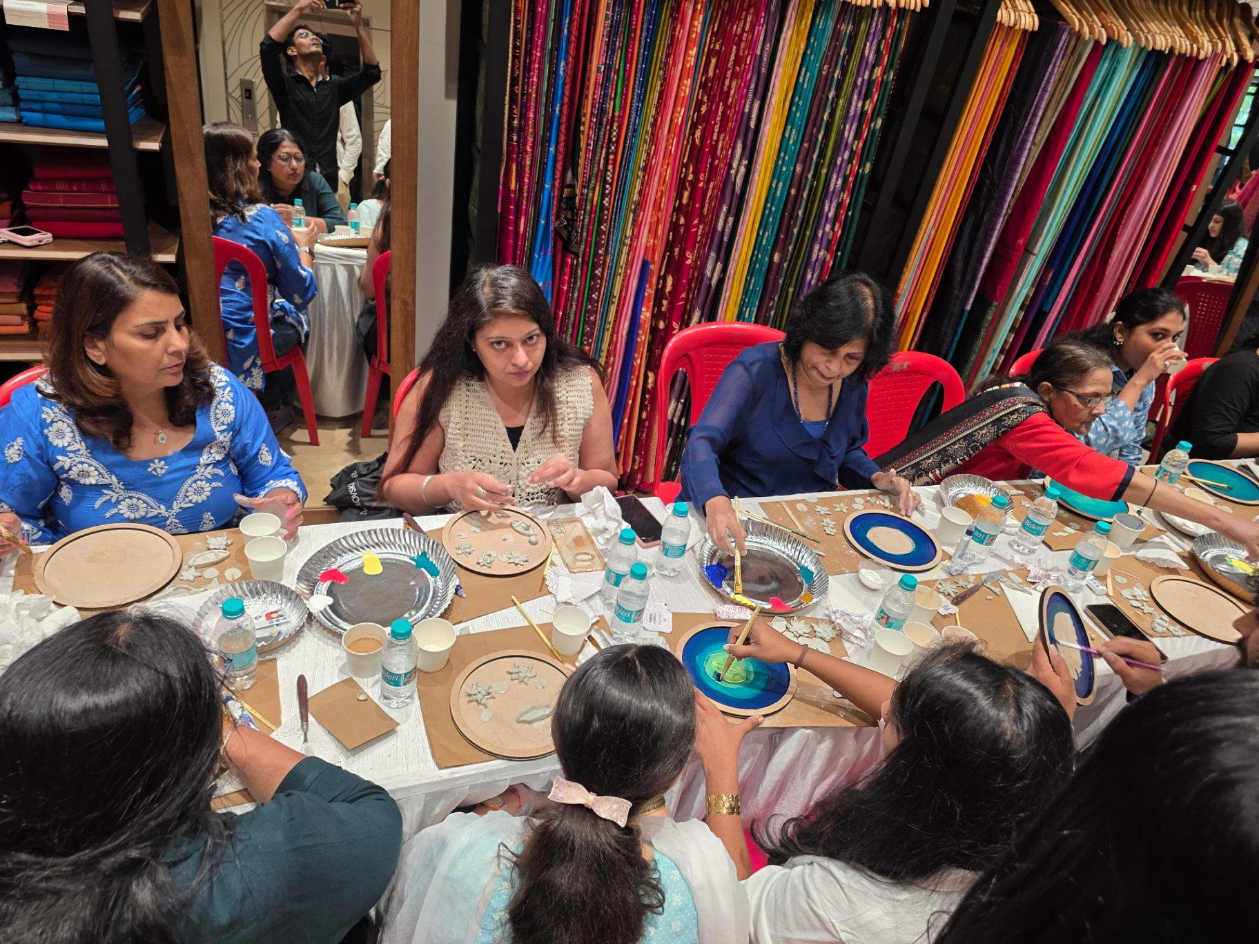 A busy workshop table filled with participants creating decorative pieces